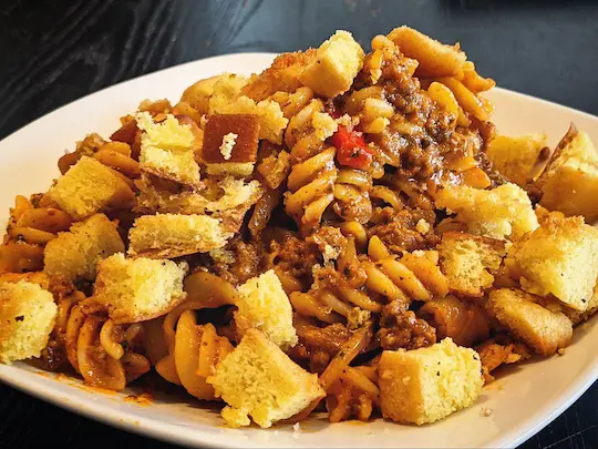 A pasta dish with mince meat, croutons, bell peppers, and more.